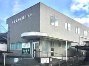 介護施設の建物外観。グレーのモダンな2階建て施設で、玄関入口が見える。